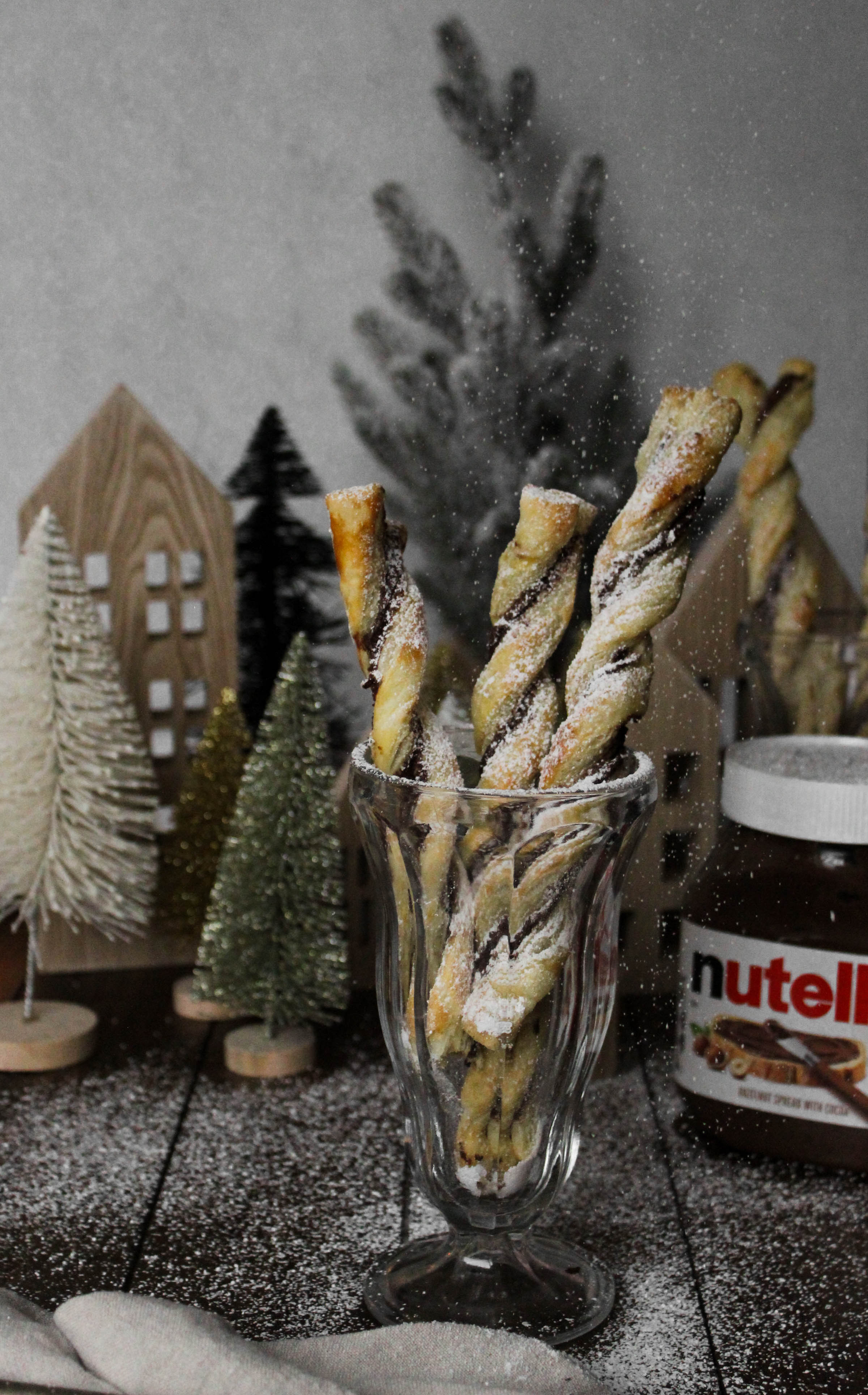 straight view of Nutella twists in a glass with Christmas scene behind.